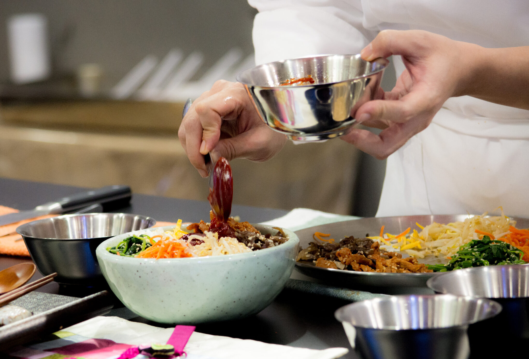 Chef preparing Bibimbap, Korean food, in a modern kitchen.